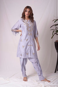Buy lavender embroidered chanderi suit online in USA. Suit has simple golden work. Kurta has 3/4 length sleeves with net like at border, dhoti and rhombus neckline. Simple look makes it elegant. Be the talk of parties and weddings with exquisite designer gowns from Pure Elegance Indian clothing store in USA. Shop online now.-full view