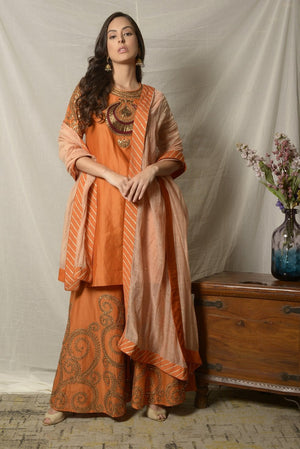 Buy stunning burnt orange embroidered chanderi sharara suit online in USA with dupatta. Shine at weddings and special occasions with beautiful Indian designer suits, gowns, lehengas from Pure Elegance Indian clothing store in USA.-front