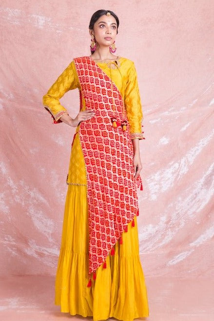 Shop stunning yellow designer sharara suit online in USA with red draped Bandhej dupatta. Champion ethnic fashion on weddings and festivals with a stunning collection of designer Indian dresses, Indowestern outfits, salwar suits, Anarkali suits from Pure Elegance Indian fashion store in USA.-full view