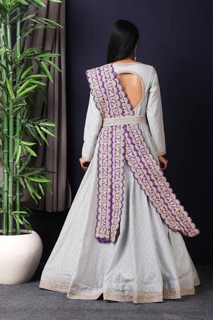 Shop this designer Indo western Anarkali in grey and purple color. This anarkali comes in chanderi silk fabric which has zari dori work around neck and maharani belt with embroidery work. The borders of this anarkali have an exquisite design that is eye-catchy and has lace work on it. Buy designer anarkali attire from Pure Elegance Indian saree store in USA.-Back view.