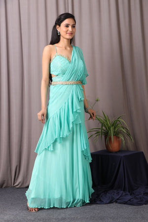Shop this designer indo western Saree in aqua blue colour. This saree comes in chiffon and upadda silk fabric. The borders of the saree have an exquisite design that is eye-catchy and has sequin and thread embroidery work on it. Complete the look with embroidered blouse showcasing floral and animal motifs especially around the neckline and on the backside. Shop this designer from Pure Elegance Online Indian store now.-Side view.