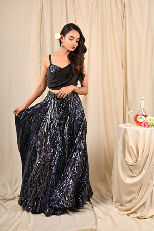 Shop this gorgeous black lehenga with drape blouse from Pure Elegance featuring sequin work and a beautiful neckline. Made with premium quality georgette and sequin fabric, this set contains a designer drape blouse, a lehenga. Pair it up with statement jewellery to complete your lookbook this season Style this set with a pair of diamond earrings and solid pumps to finish the look from Pure Elegance Indian clothing store in USA online now.-Full view.