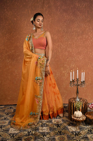 Shop this gorgeous safrron lehenga choli from Pure Elegance featuring intricate embroidery and a V-neck. Made with premium quality georgette and silk fabric, this set contains a choli, a lehenga, and a dupatta. Pair it up with statement jewellery to complete your lookbook this season Style this set with a pair of diamond earrings and solid pumps to finish the look from Pure Elegance Indian clothing store in USA online now.-Side view.