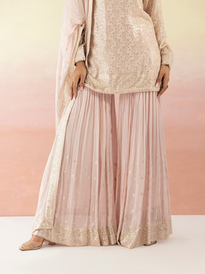 Shop beautiful powder pink sequin embellished sharara suit online in USA with dupatta. Make a fashion statement on festive occasions and weddings with designer suits, Indian dresses, Anarkali suits, palazzo suits, designer gowns, sharara suits from Pure Elegance Indian fashion store in USA.-sharara