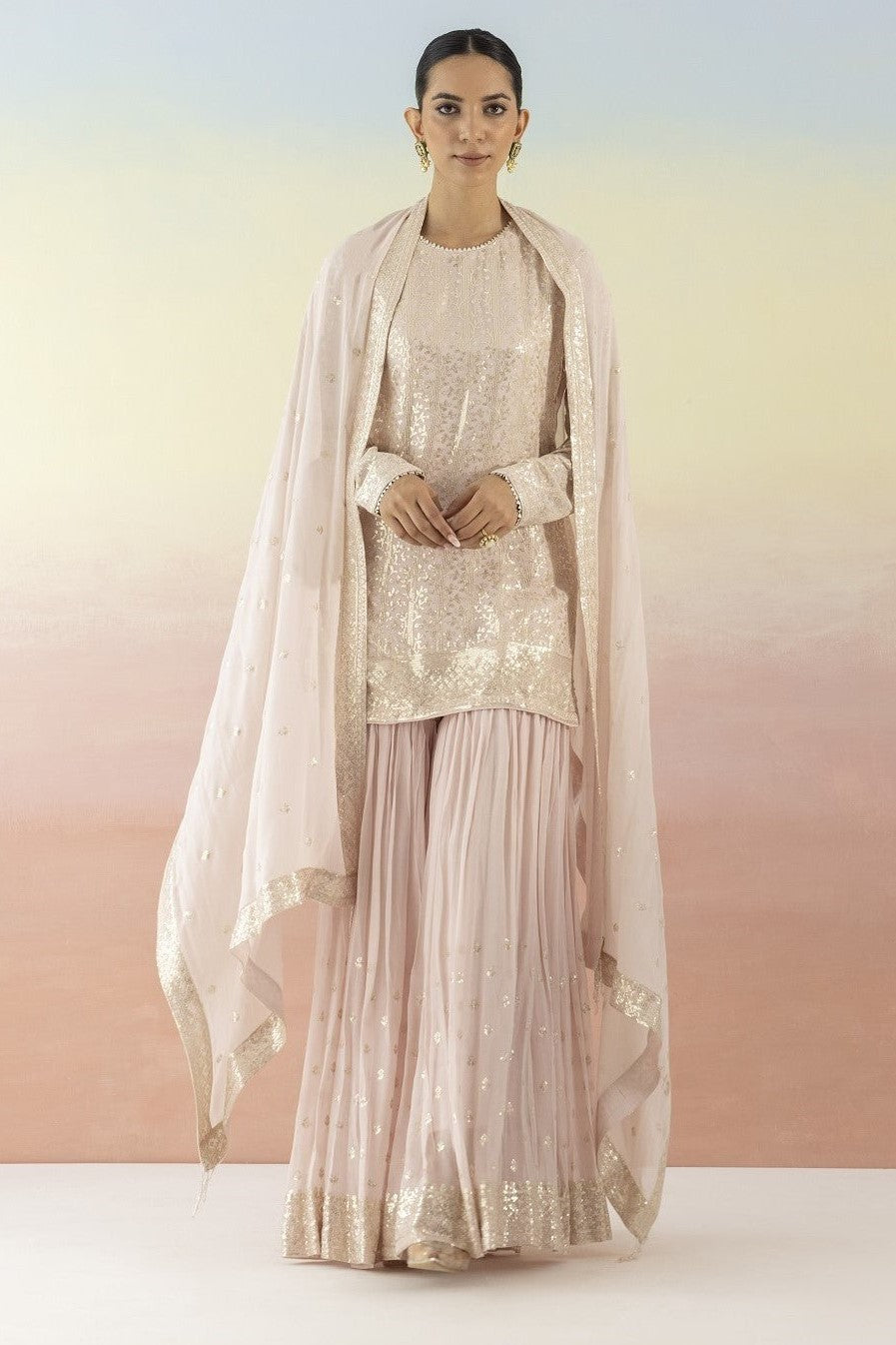 Shop beautiful powder pink sequin embellished sharara suit online in USA with dupatta. Make a fashion statement on festive occasions and weddings with designer suits, Indian dresses, Anarkali suits, palazzo suits, designer gowns, sharara suits from Pure Elegance Indian fashion store in USA.-full view