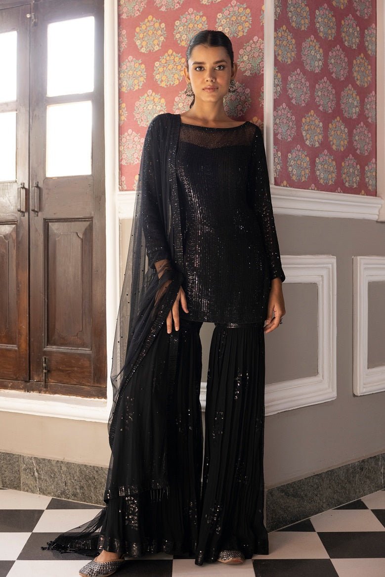 Shop beautiful black embroidered sequin sharara suit online in USA with dupatta. Dazzle on weddings and special occasions with exquisite Indian designer dresses, sharara suits, Anarkali suits, bridal lehengas, sharara suits from Pure Elegance Indian clothing store in USA.-front