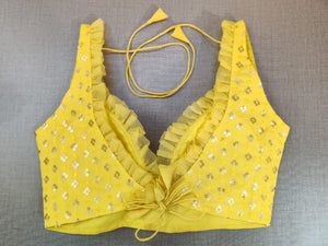 Buy a tap into the festive mood with this yellow blouse that is spruced up with gleaming details. Tailored in silk with a strappy neck, the blouse is adorned with golden foil work and frills on the neck in the front and back making the blouse more elegant. Buy this designer blouse in the USA from Pure Elegance. - Back View