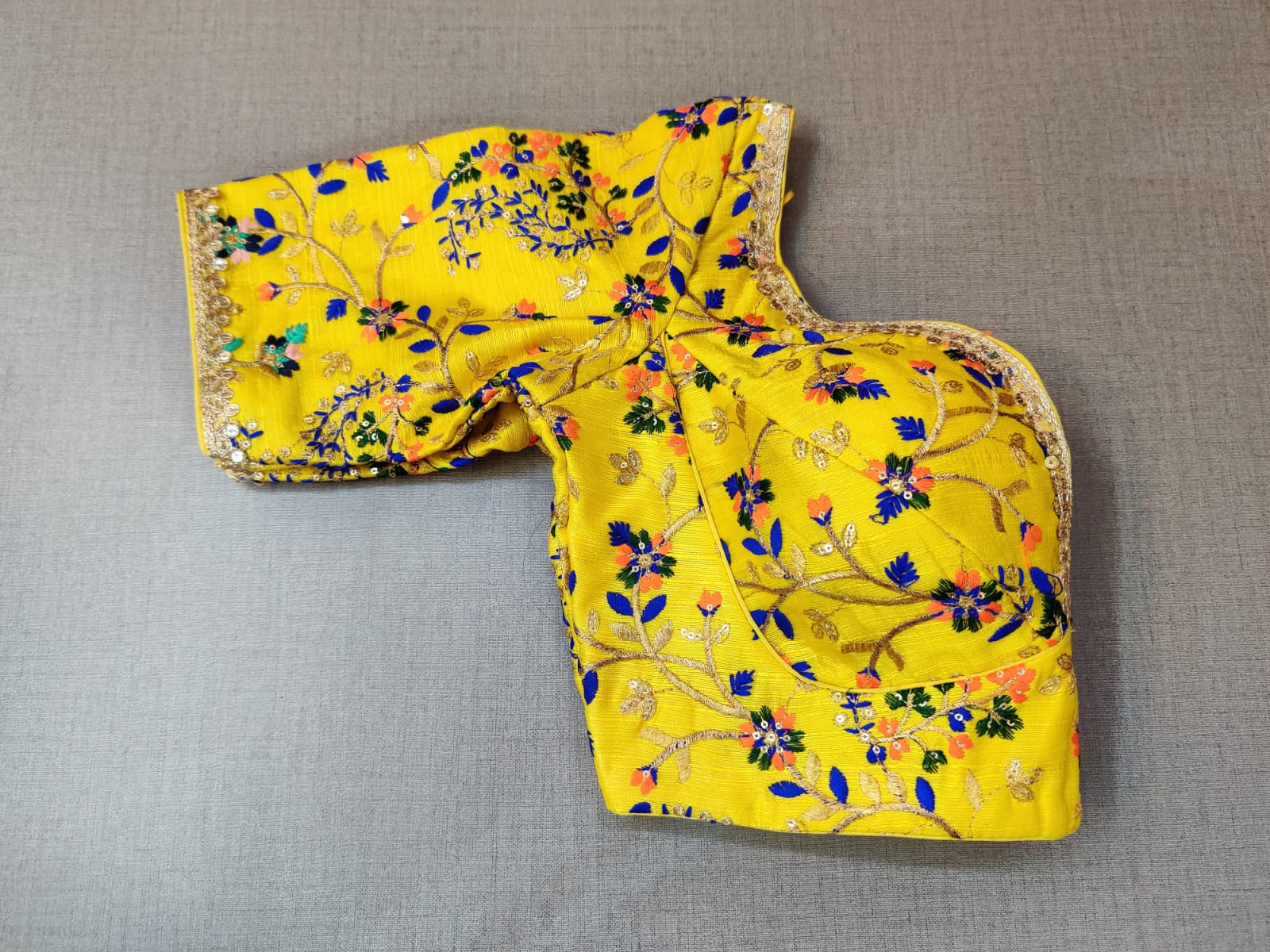 Buy a yellow silk saree blouse that has a sweetheart neck, 3/4th sleeves, and hook closure. Yellow blouse crafted in hammered silk with beautiful floral embroidery work. This charming blouse surely fetches you compliments for your rich sense of style. Complement your look with statement jewelry and high heels to complete the ensemble.- Folded View