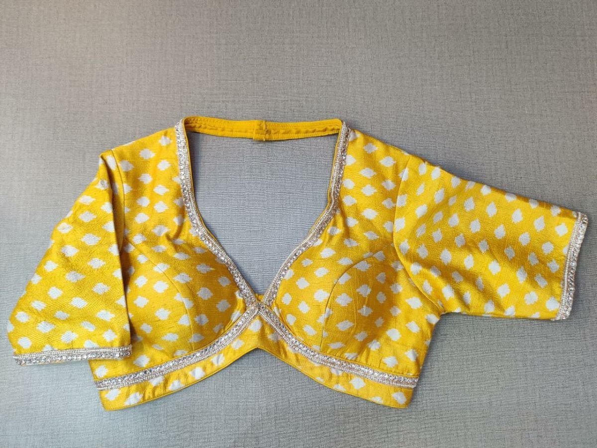 Buy this look in the gaiety of spring with this enchanting yellow blouse. Tailored in silk, it features a white polka dot print and neck embroidery and gets its finishing touches with hook closure at the back. Perfect blouse for Haldi functions. Elevate your Indian saree style with exquisite readymade sari blouse, embroidered saree blouses, Banarasi sari blouse, and designer sari blouse from Pure Elegance Indian clothing store in the USA.- Front View
