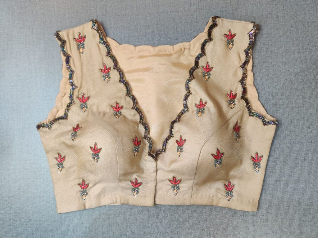 Buy this festive essential and get an elevated twist with this beige floral embroidered blouse. Featuring an embroidered front & back, the blouse is cut with a tulip hem, V-neck, and sleeveless. Wear it with a contrasting saree or even with a contrasting lehenga skirt to complete the look.- Front View