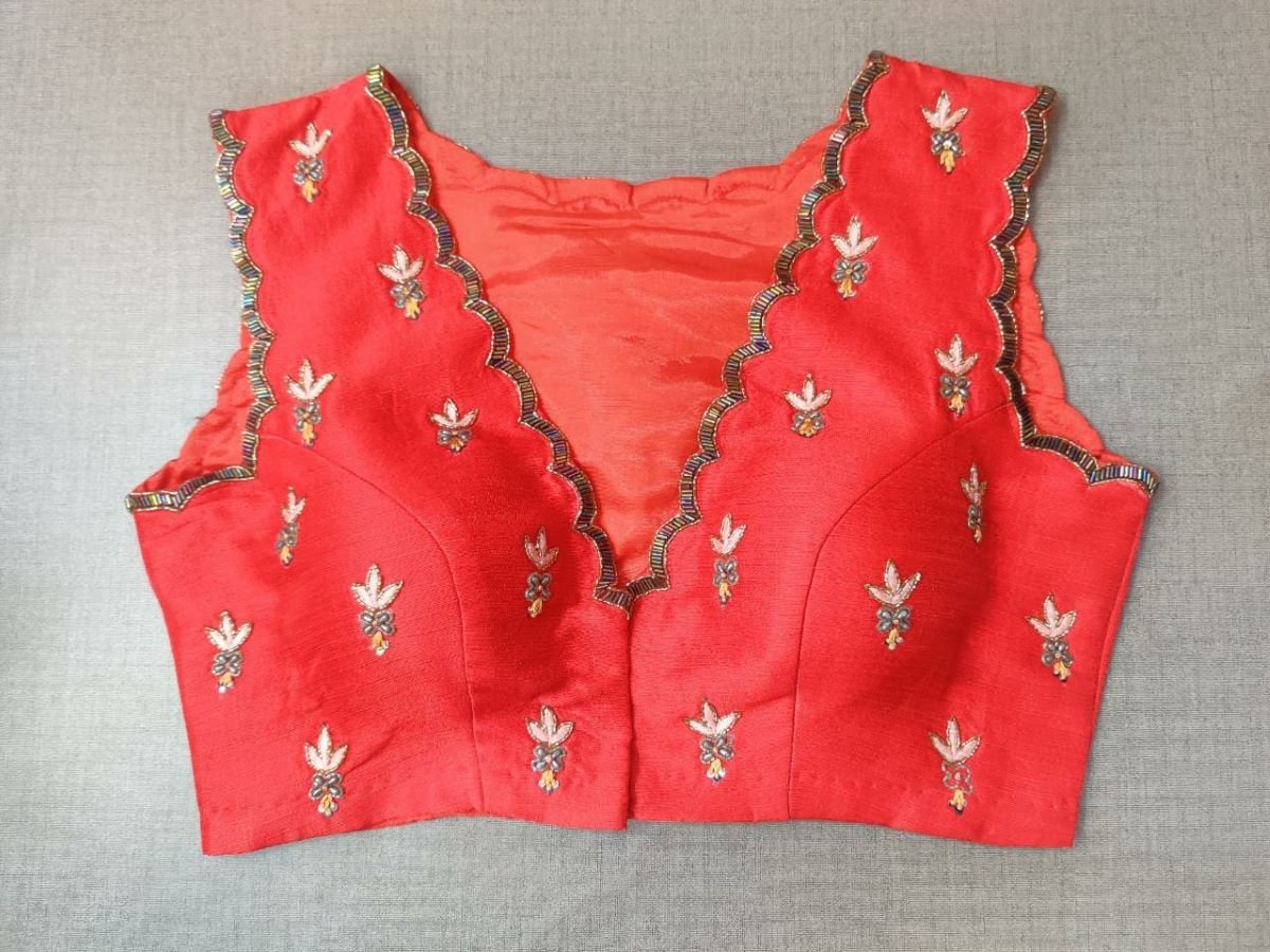 Buy this festive essential and get an elevated twist with this red floral embroidered blouse. Featuring an embroidered front & back, the blouse is cut with a tulip hem, V-neck, and sleeveless. Wear it with a contrasting saree or even with a contrasting lehenga skirt to complete the look. Elevate your Indian saree style with exquisite readymade sari blouses, embroidered saree blouses, Banarasi sari blouses, and designer sari blouses from Pure Elegance Indian clothing store in the USA.-  Front View