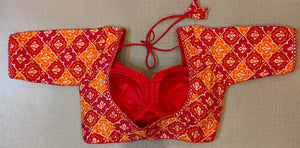 Buy women's red and orange Ajrakh Block Printed, padded Saree Blouse that has a round neck, Hook & tie-up closure at back with 3/4th sleeves. Classic is never old and enough to have in your closet!! Pair this fashionable blouse with a beautifully printed sari and statement neckpiece and you are good to go! Buy this designer blouse in the USA from Pure Elegance.- Back View