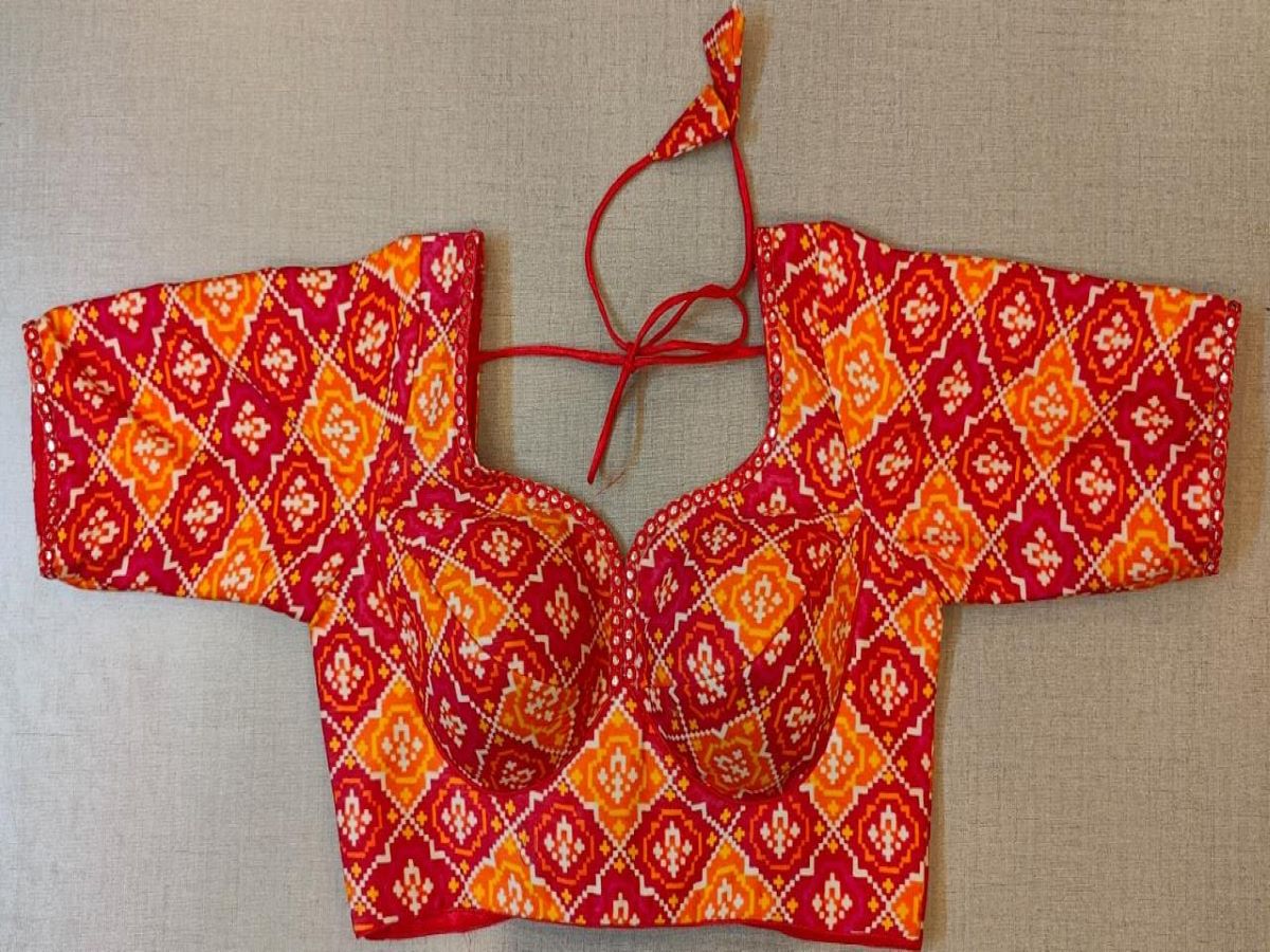 Buy women's red and orange Ajrakh Block Printed, padded Saree Blouse that has a round neck, Hook & tie-up closure at back with 3/4th sleeves. Classic is never old and enough to have in your closet!! Pair this fashionable blouse with a beautifully printed sari and statement neckpiece and you are good to go! Buy this designer blouse in the USA from Pure Elegance.- Front View
