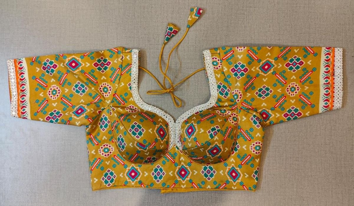 Buy women's yellow Ajrakh Block Printed, padded Saree Blouse that has a round neck, Hook & tie-up closure at back with 3/4th sleeves. Classic is never old and enough to have in your closet!! Pair this fashionable blouse with a beautifully printed sari and statement neckpiece and you are good to go! Buy this designer blouse in the USA from Pure Elegance.- Front View