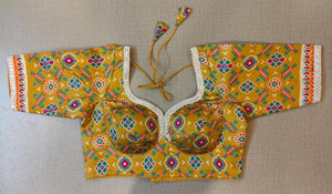 Buy women's yellow Ajrakh Block Printed, padded Saree Blouse that has a round neck, Hook & tie-up closure at back with 3/4th sleeves. Classic is never old and enough to have in your closet!! Pair this fashionable blouse with a beautifully printed sari and statement neckpiece and you are good to go! Buy this designer blouse in the USA from Pure Elegance.- Front View