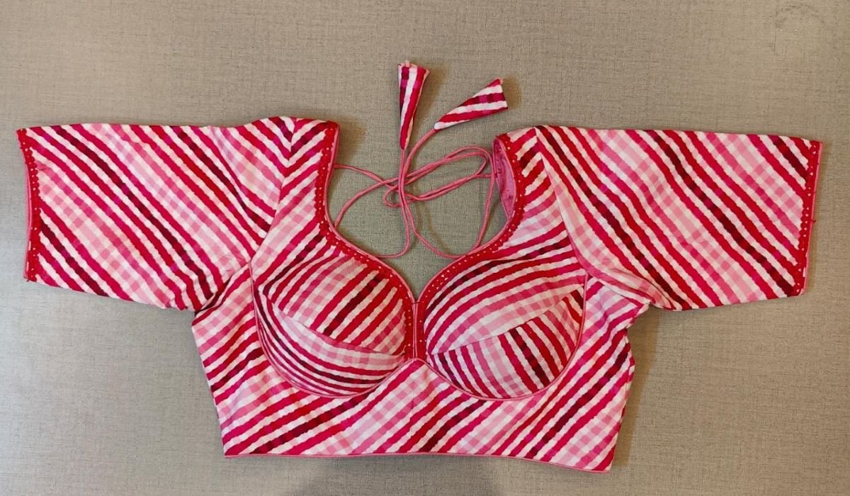 Buy pink printed saree blouse, has a U-neck, short sleeves, a hook, and a tie-up closure at the back. Drape a saree over this pretty blouse and be the start of any function. You can also style it with a palazzo to create a fusion outfit. Elevate your Indian saree style with exquisite readymade sari blouses, embroidered saree blouses, Banarasi sari blouses, and designer sari blouses from Pure Elegance Indian clothing store in the USA.- Front View