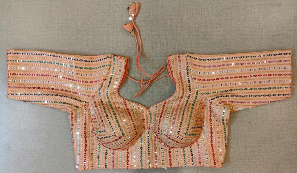 Buy a peach multicolor sequinned saree blouse, that has a U-neck, short sleeves, a hook, and a tie-up closure at the back. Drape a saree over this pretty blouse and be the start of any function. You can also style it with a palazzo to create a fusion outfit.  Elevate your Indian saree style with exquisite readymade sari blouses, embroidered saree blouses, Banarasi sari blouses, and designer sari blouses from Pure Elegance Indian clothing store in the USA.- Front View