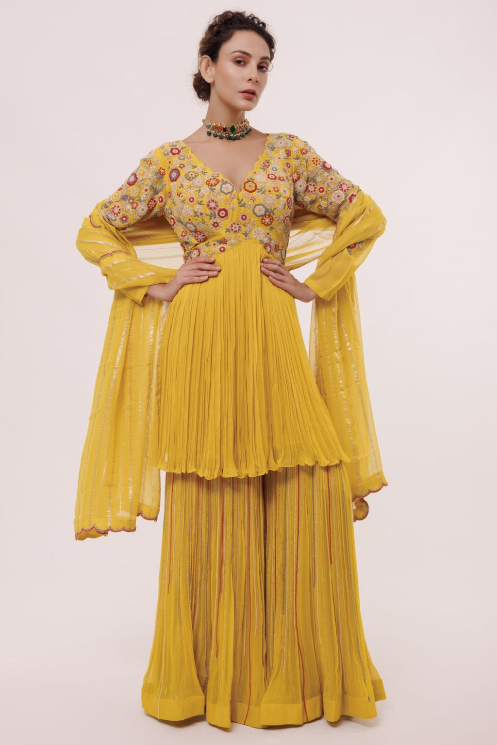Buy this Look your best on festive occasions in this beautiful yellow georgette suit with a floral peplum top and pleated sharara with multicolor pearl. It comes with a matching organza dupatta. Dazzle on weddings and special occasions with exquisite Indian designer dresses, sharara suits, Anarkali suits, and wedding lehengas from Pure Elegance Indian fashion store in the USA.