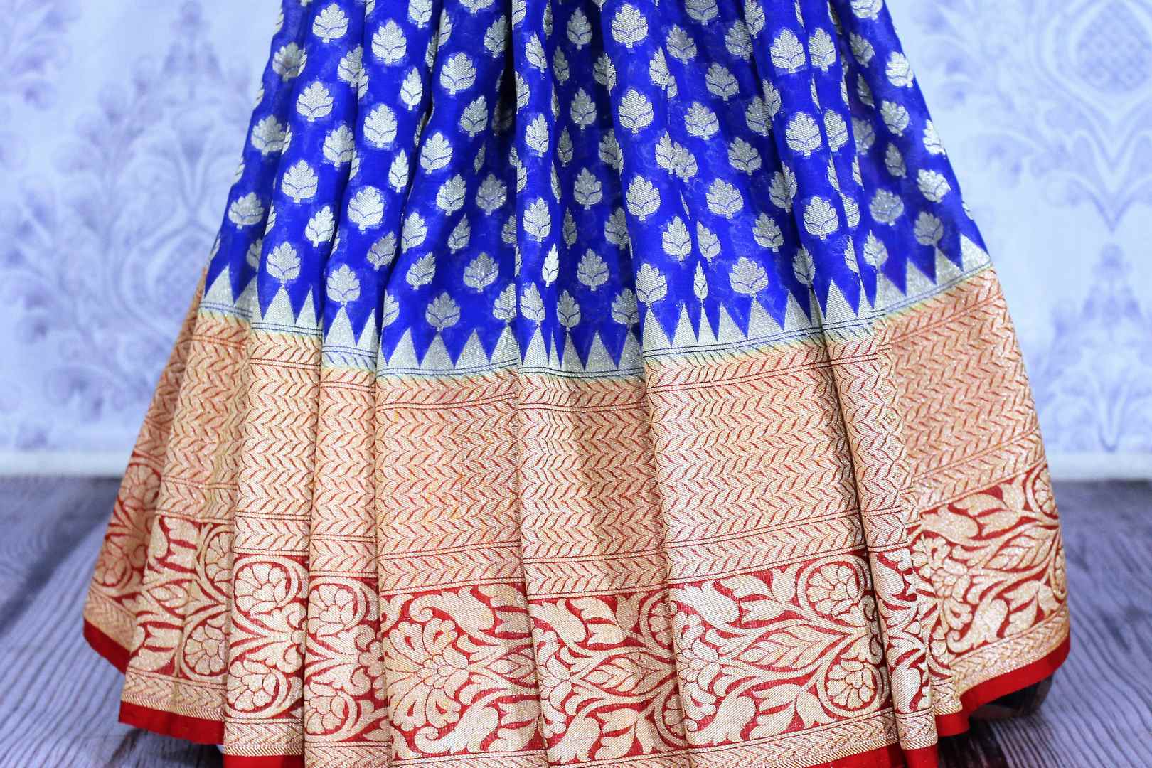 Buy blue georgette Banarasi saree online in USA. The alluring design of the saree with red zari border and buta makes it perfect for parties and festivals. Select from an exquisite collection of traditional Indian Banarasi sarees, designer saris at Pure Elegance clothing store or shop online.-pleats