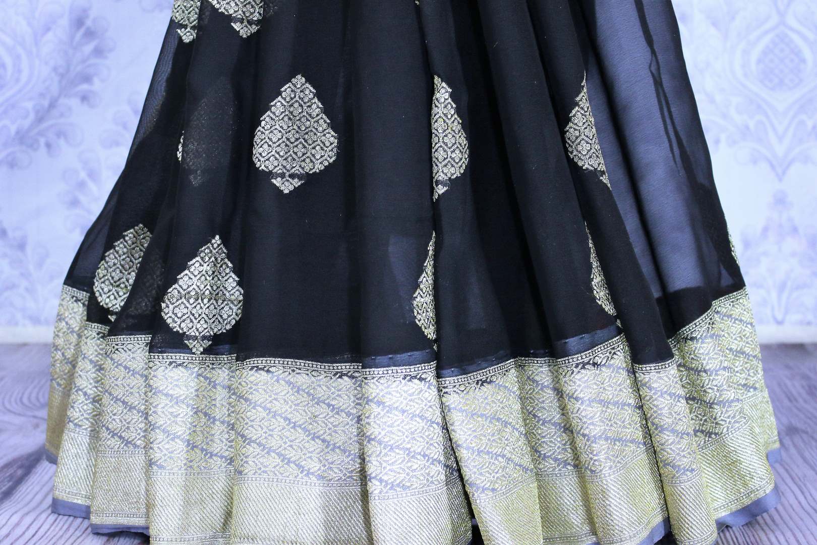 Black georgette Banarasi saree with silver buta for online shopping in USA. The traditional saree is contrasted with a light blue zari border which makes it so captivating. Select from an exquisite collection of traditional Indian Banarasi sarees, designer sarees at Pure Elegance clothing store or shop online.-pleats