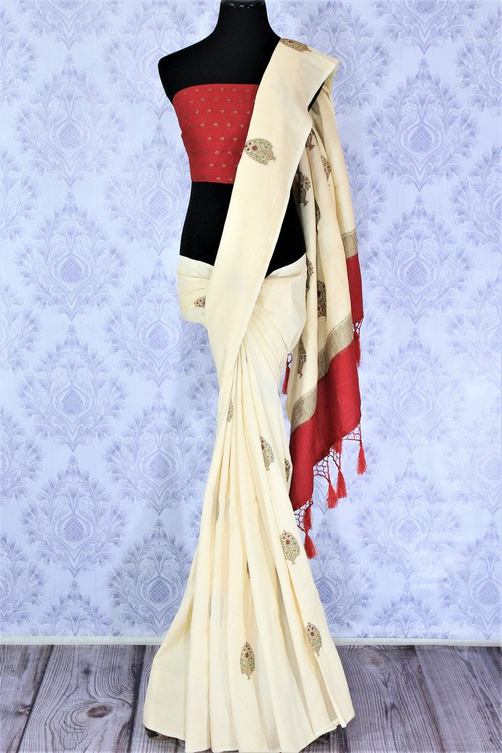 Embrace the uniqueness of this sartorial cream embroidered muga banarsi silk saree. Drape this traditional white and red Indian silk sari to weddings and festivities with a striking red buta work blouse. Shop designer silk sarees, ikkat saris, printed sarees online or visit Pure Elegance store, USA. -full view
