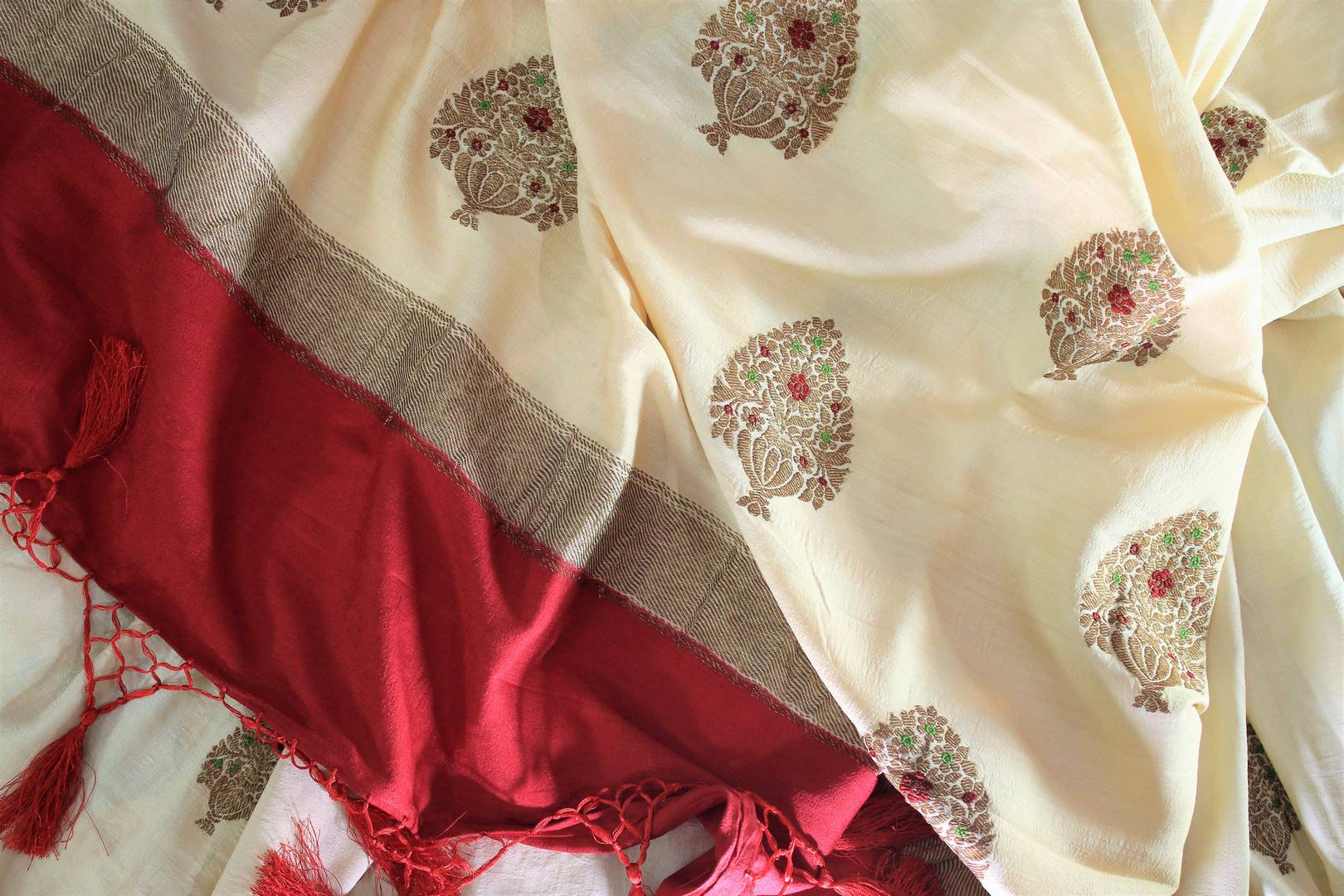 Embrace the uniqueness of this sartorial cream embroidered muga banarsi silk saree. Drape this traditional white and red Indian silk sari to weddings and festivities with a striking red buta work blouse. Shop designer silk sarees, ikkat saris, printed sarees online or visit Pure Elegance store, USA. -details
