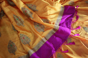 Escalate your style game with this exquisitely designed orange embroidered muga banarsi silk sari. Pair this stunning saree with pink raw silk and embroidered blouse complemented with purple border and embroidery. Shop designer silk sarees, printed saris, banarsi saris online or visit Pure Elegance store in USA. -details