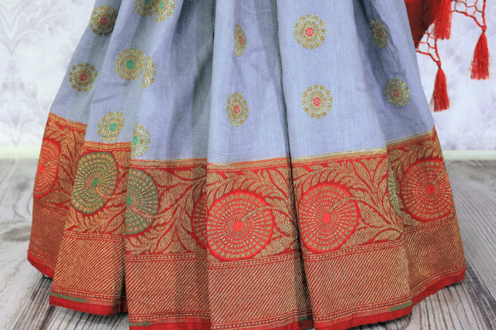 Generously tailored for women with substance, this grey designer muga banarsi silk saree is perfect for weddings and festivities. It comes with a zari border and contrasting red designer blouse and a woven pallu. Shop designer silk saris, ikkat sarees, printed saris online or visit Pure Elegance store in USA. -pleats