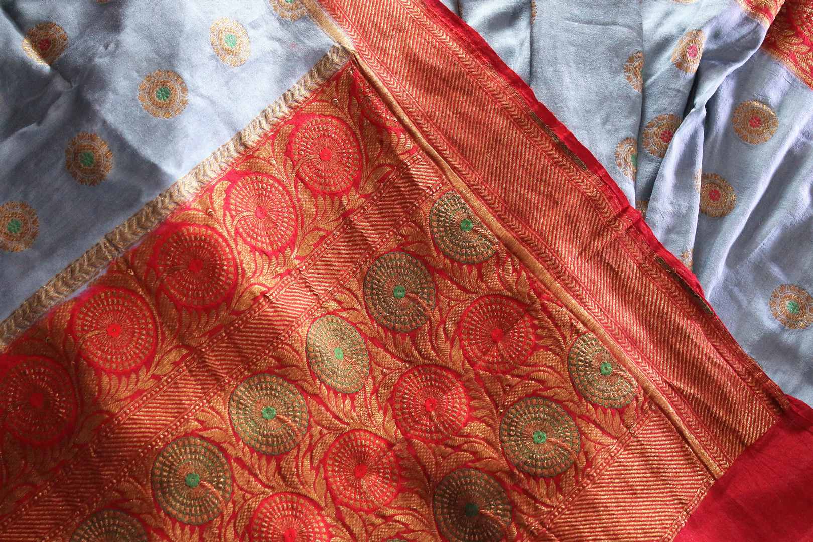 Generously tailored for women with substance, this grey designer muga banarsi silk saree is perfect for weddings and festivities. It comes with a zari border and contrasting red designer blouse and a woven pallu. Shop designer silk saris, ikkat sarees, printed saris online or visit Pure Elegance store in USA. -details