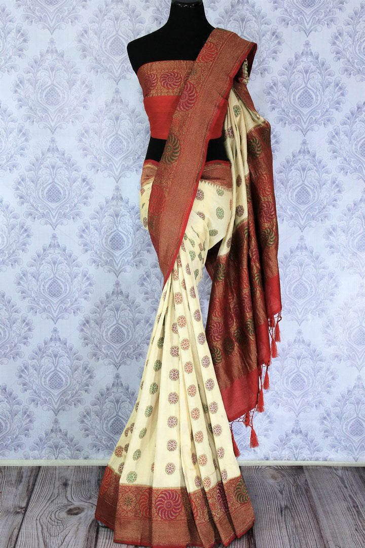 Grace the gala soirees in this bespoke designer cream floral embroidered muga banarsi silk saree. Style this breath-taking drape with a contrasting red woven silk designer blouse. Shop designer silk sarees, ikkat saris, banarsi sarees online or visit Pure Elegance store in USA.-full view
