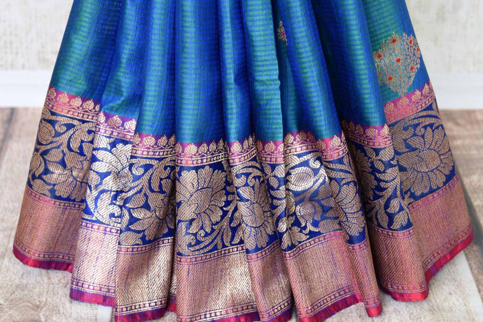 Indulge in the ethereal beauty of this royal blue tussar banarsi silk saree which comes with buta work and zari border. Style it with a designer blouse and steal the limelight as you sashay in a heavily embroidered pallu. Shop handloom sarees, georgette sari, ikkat saree online or visit Pure Elegance store, USA. -pleats