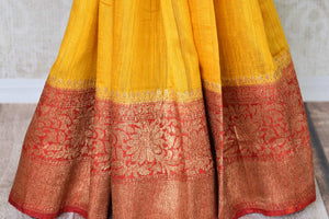 Exude a flair of elegance in this scintillating bright yellow matka banarsi silk saree. It comes with a gorgeous red zari border and complemented well with a contrasting red zari designer blouse. Shop handcrafted silk sarees, linen sari, georgette saree online or visit Pure Elegance store, USA.-pleats