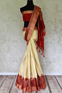 Unleash the royalty in you draping this cream matka banarsi silk sari. It comes with a gorgeous red zari border and a contrasting red blouse. The heavily woven pallu further enhances the beauty of this sari. Shop designer printed sarees, silk sari, linen saree online or visit Pure Elegance store, USA.-full view