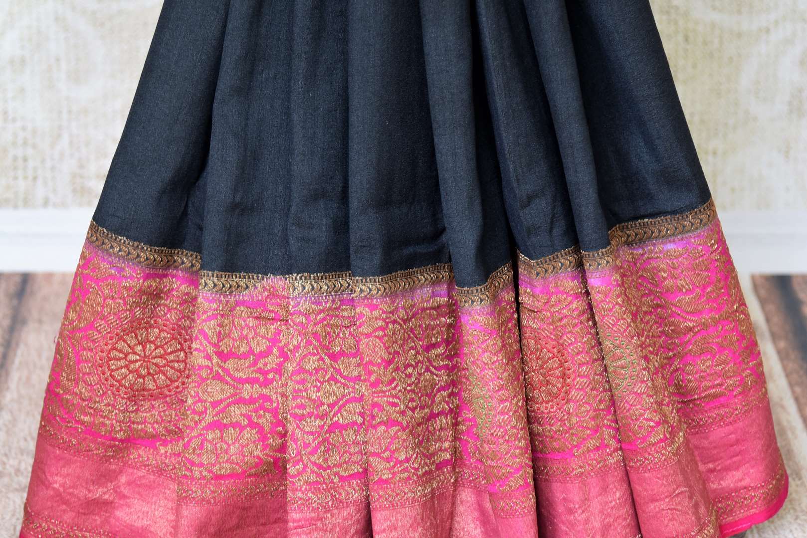 Strut the town in this glorious black muga silk saree curated with finesse. Style this sari with a gorgeous contrasting pink plain blouse that complements the pink zari border and heavily woven pallu. Shop banarsi silk sarees, embroidered sari, georgette sari online or visit Pure Elegance store, USA.-pleats