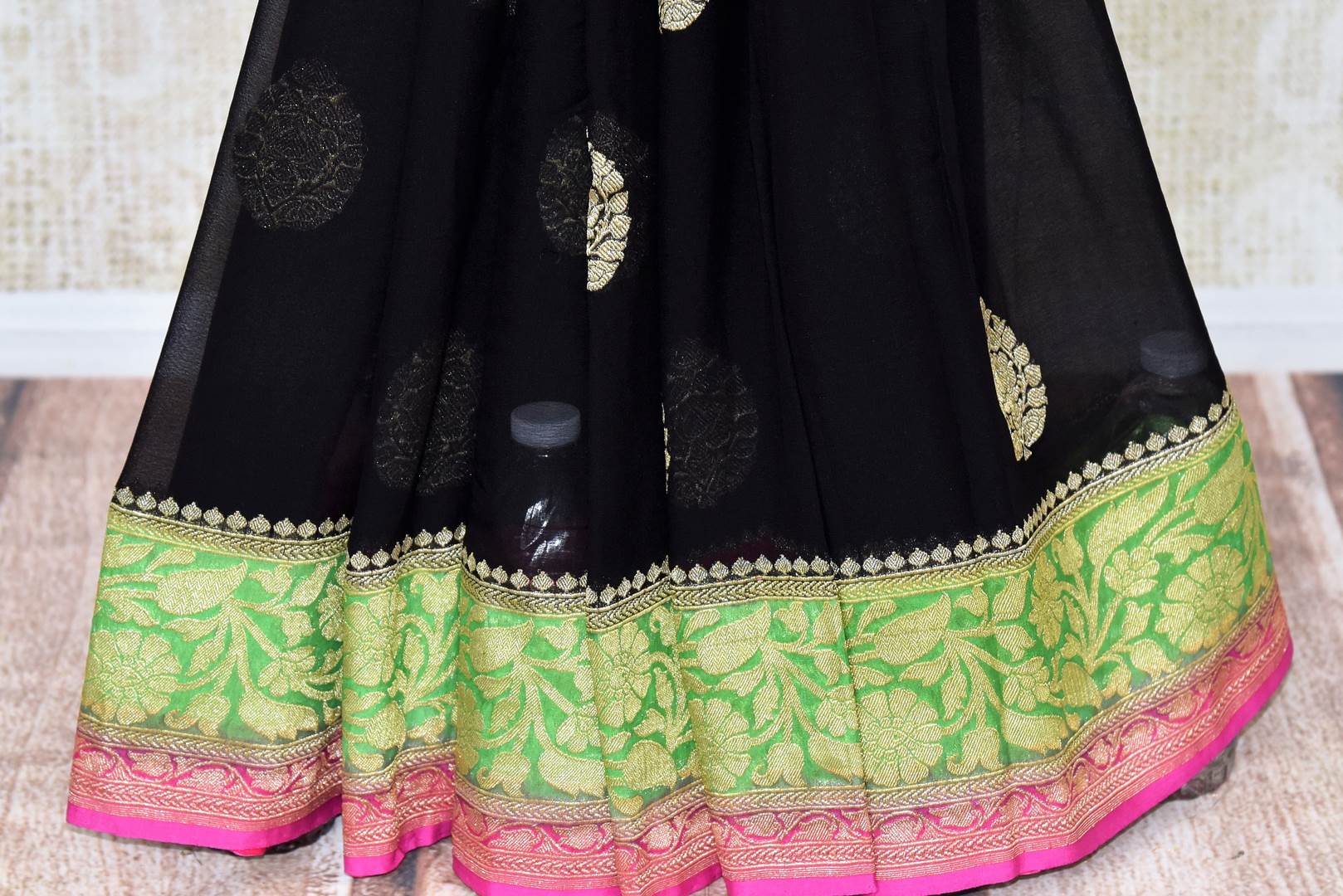 Shop black georgette Benarasi sari online in USA with green pink floral zari border from Pure Elegance online store. Visit our exclusive Indian clothing store in USA and get floored by a range of exquisite pure handloom sarees, Banarasi sarees, silk sarees, Indian jewelry and much more to complete your ethnic look.-pleats