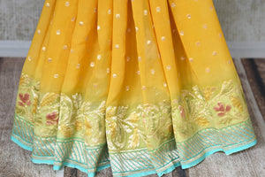 Shop yellow Banarasi georgette saree online in USA with floral zari border from Pure Elegance online store. Visit our exclusive Indian fashion store in USA and get floored by a range of exquisite pure handloom sarees, Banarasi sarees, silk sarees, Indian jewelry and much more to complete your ethnic look.-pleats
