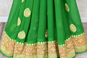 Shop green georgette Banarasi sari online in USA with floral zari buta and foliate zari border. Elevate your traditional saree style with beautiful Indian Banarasi saris from Pure Elegance Indian fashion store in USA. We also have a stunning variety of bridal saris for Indian brides in USA. Shop now.-pleats