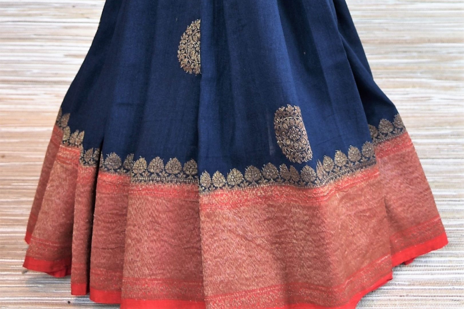 Buy navy blue muga Benarasi sari online in USA with zari buta and zari border. Radiate traditional charm with beautiful Banarasi sarees from Pure Elegance Indian clothing store in USA. Choose from a variety of handwoven saris, Banarasi silk sarees, Banarasi georgette sarees, Banarasi tussar saris for special occasions.-pleats