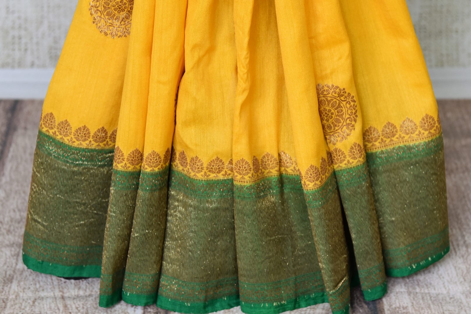 Buy yellow muga Banarasi saree online in USA with green antique zari border. Be an epitome of elegance in exquisite Banarasi sarees from Pure Elegance Indian clothing store in USA.-pleats
