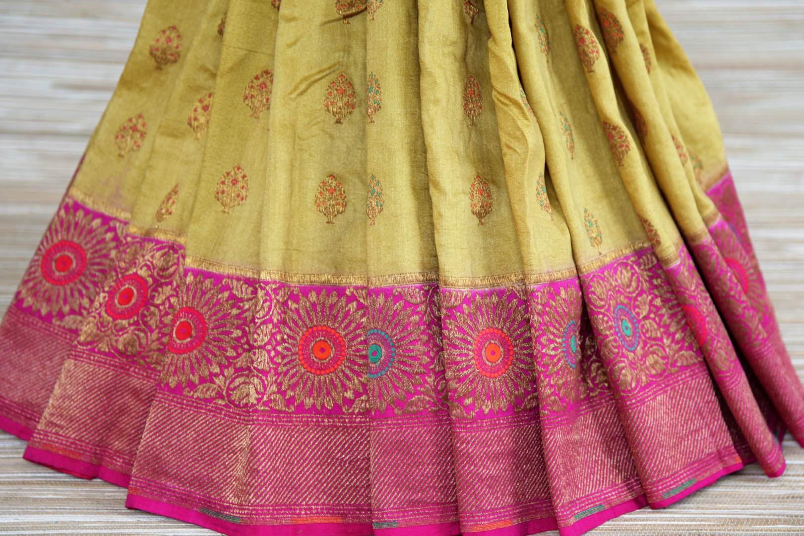 Buy pista green muga Banarasi saree online in USA with pink zari minakari border. Radiate traditional charm with beautiful Banarasi sarees from Pure Elegance Indian clothing store in USA. Choose from a variety of Banarasi silk sarees, Banarasi georgette sarees, Banarasi tussar saris for special occasions.-pleats