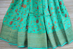 Buy green muga Benarasi sari online in USA with floral minakari zari design. Radiate traditional charm with beautiful Banarasi sarees from Pure Elegance Indian clothing store in USA. Choose from a variety of Banarasi silk sarees, Banarasi georgette sarees, Banarasi tussar saris for special occasions.-pleats
