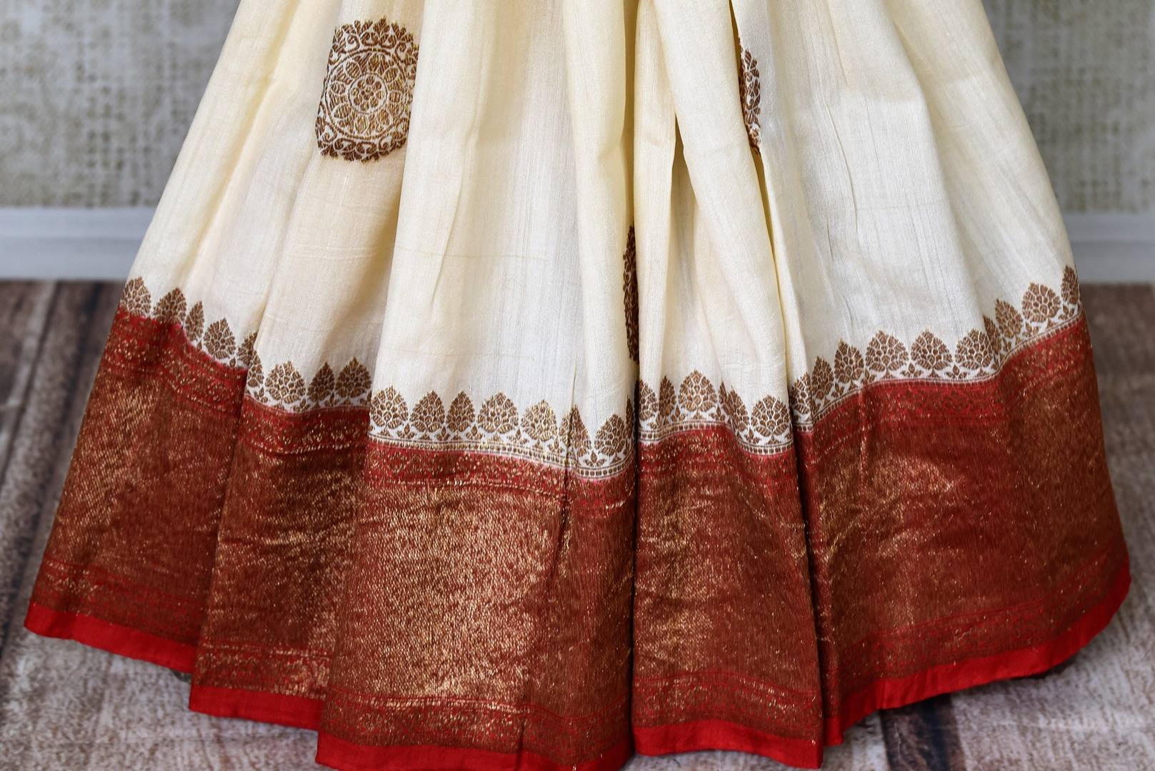 Buy off-white muga Banarasi sari online in USA with zari buta and red antique zari border and pallu. Be an epitome of elegance in exquisite Banarasi saris from Pure Elegance Indian clothing store in USA.-pleats