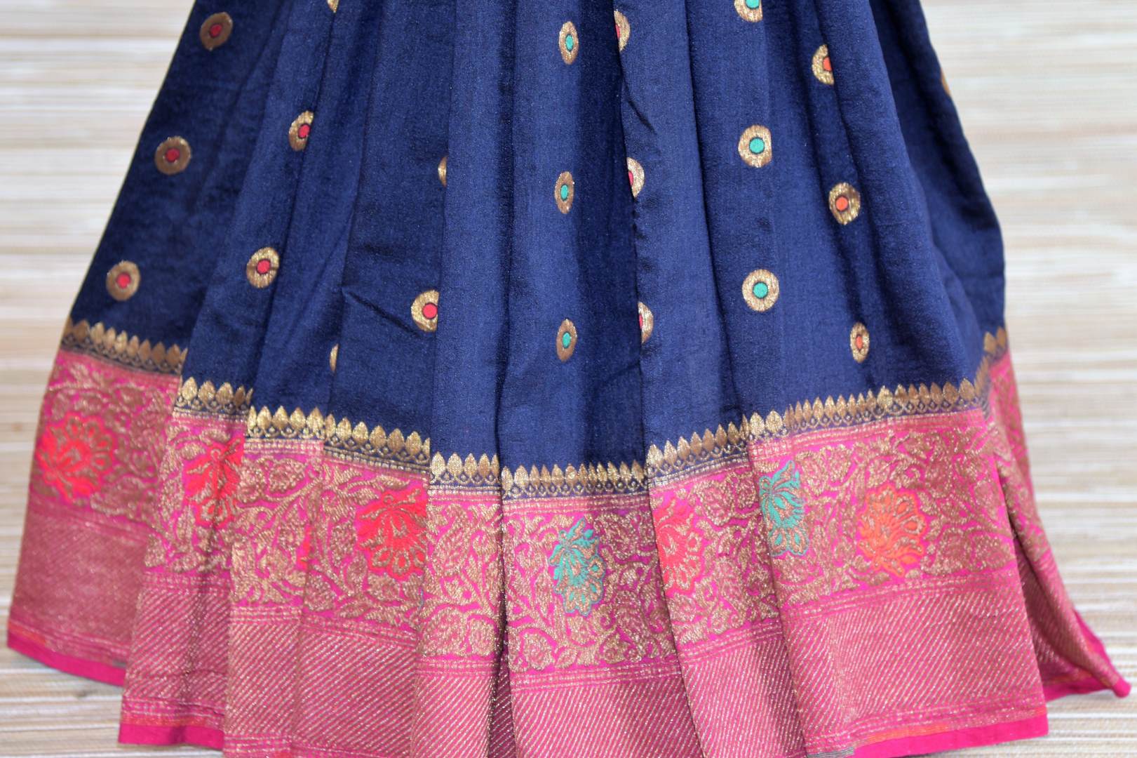 Buy dark blue muga Banarasi saree online in USA with pink minakari zari border. Radiate traditional charm with beautiful Banarasi sarees from Pure Elegance Indian clothing store in USA. Choose from a variety of Banarasi silk sarees, Banarasi georgette sarees, Banarasi tussar saris for special occasions.-pleats