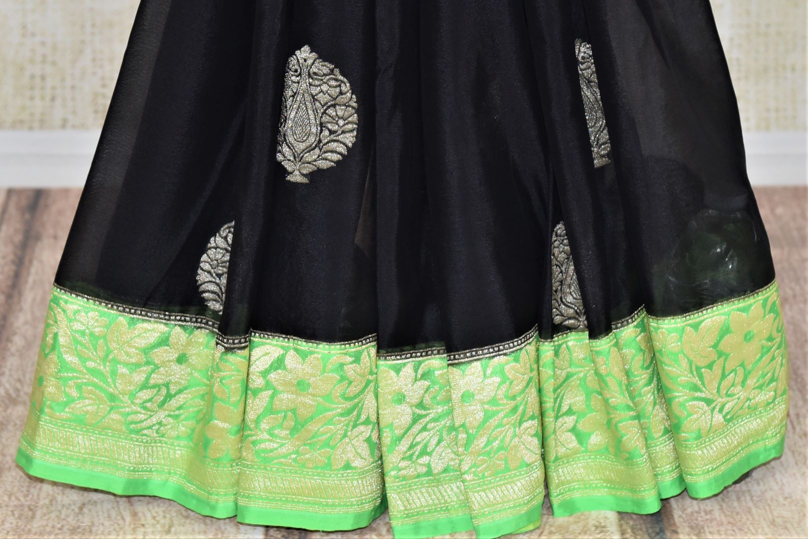 Buy elegant black georgette Banarasi saree online in USA with green foliate zari border. Go for an extraordinary traditional look with splendid handwoven sarees, embroidered sarees with blouses, Banarasi saris from Pure Elegance from Indian cloth store in USA.  Shop online or visit our store now.-pleats