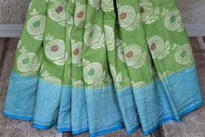 Shop light green muga Benarasi saree online in USA with blue zari border and marigold buta. Make your saree wardrobe rich and colorful with stunning handwoven sarees, pure silk sarees, designer sarees from Pure Elegance Indian clothing store in USA.-pleats