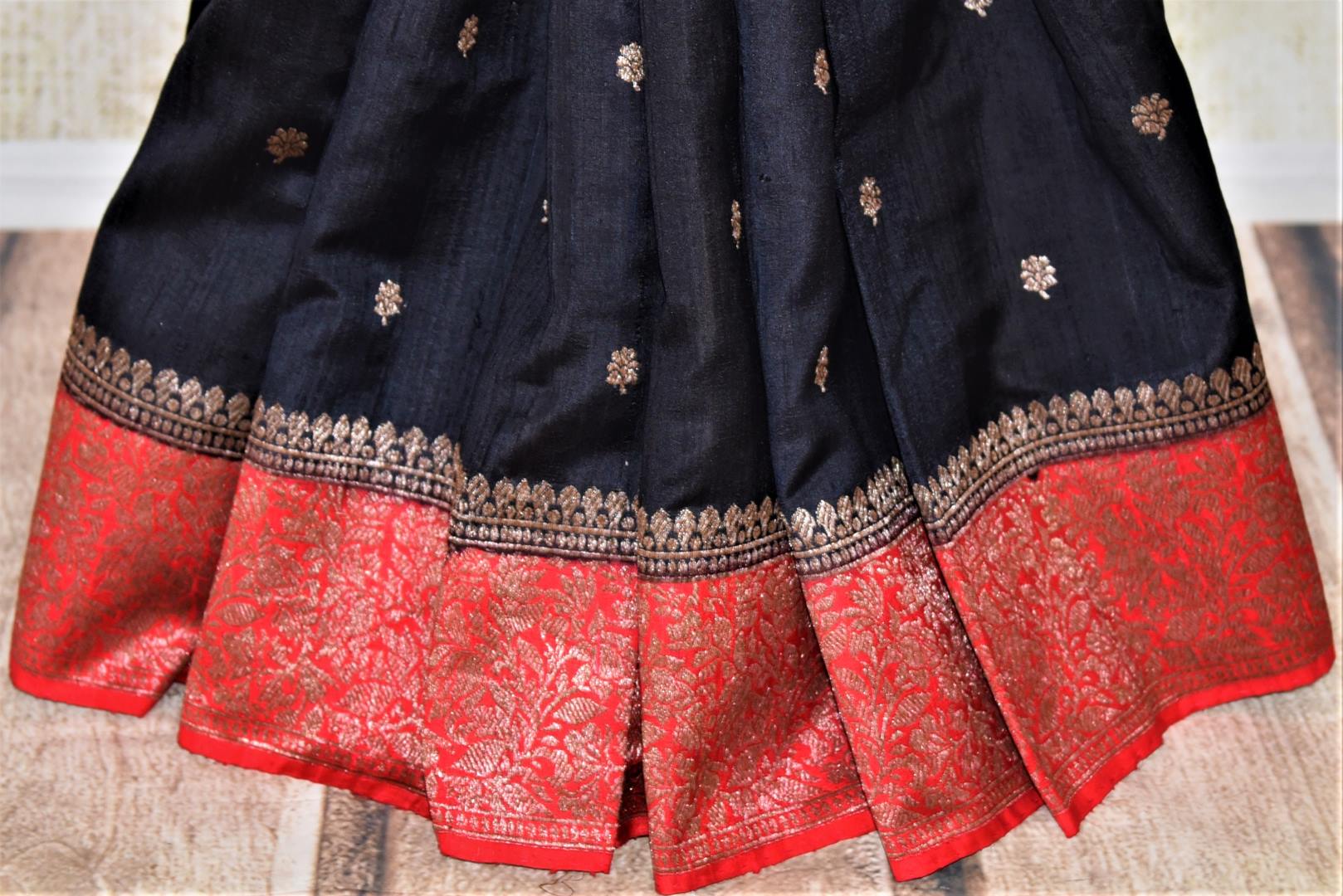 Buy black tussar Banarasi sari online in USA with zari buta and red zari border. Choose tasteful handloom saris for special occasions from Pure Elegance. Our exclusive Indian fashion store has a myriad of exquisite pure silk saris, tussar sarees, Banarasi sarees for Indian women in USA.-pleats