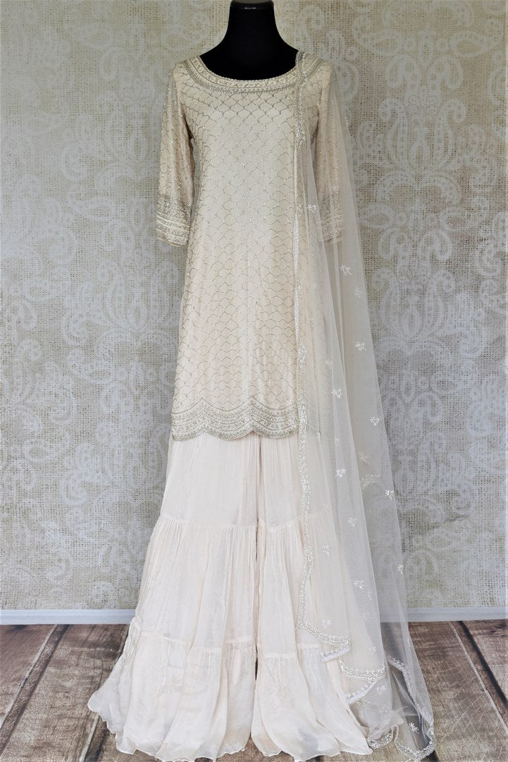 Shop beautifull cream hand embroidered silk sharara suit online in USA with dupatta. Elevate your ethnic style on weddings and festive occasions with stunning designer Anarkali suits, sharara suits, palazzo suits, salwar suits from Pure Elegance Indian fashion boutique in USA.-full view