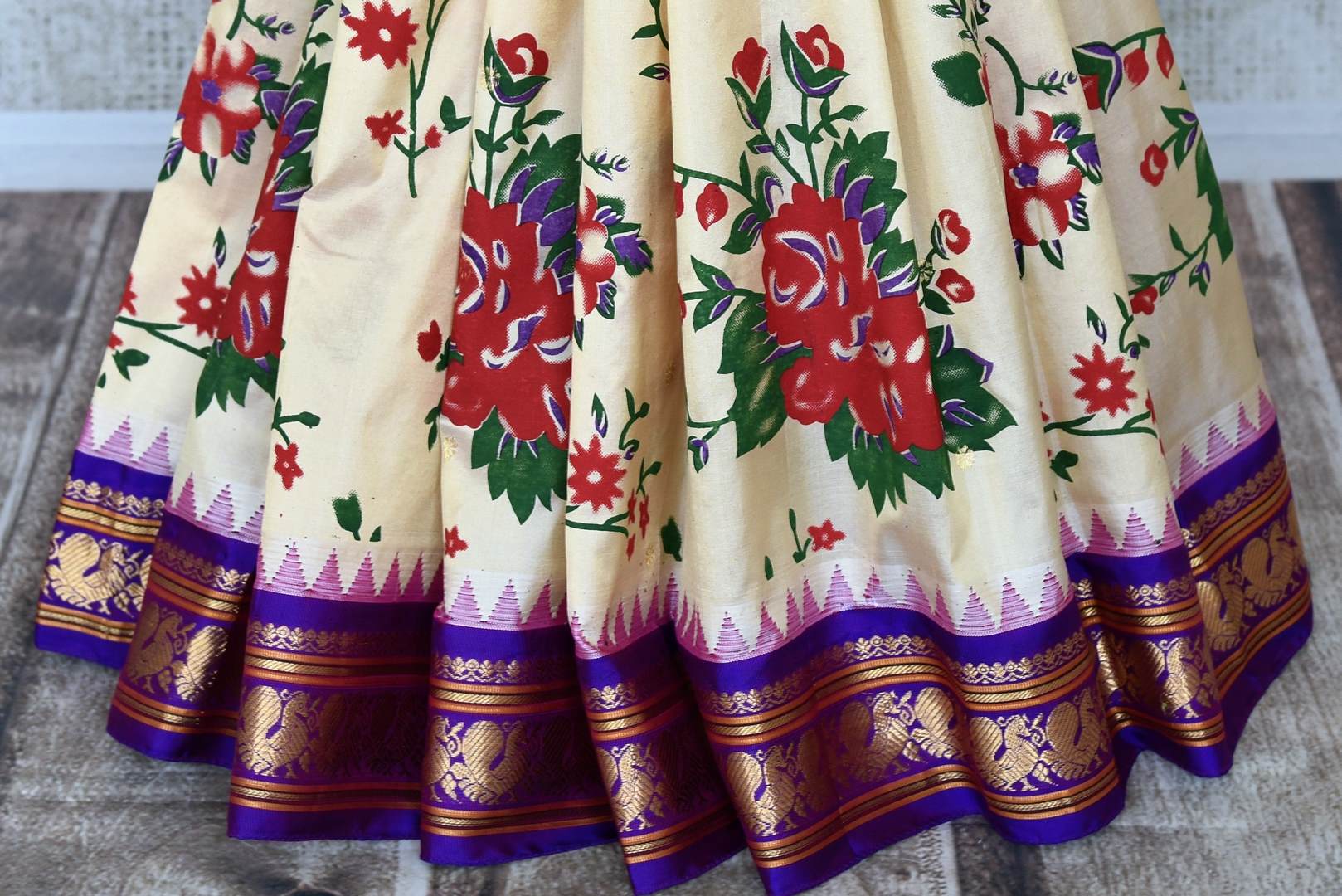 Shop beautiful cream floral print Gadhwal silk saree online in USA with purple zari border. Be the center of attraction at weddings and special occasions in exquisite designer sarees, handwoven silk saris, organza sarees, pure silk saris from Pure Elegance Indian fashion store in USA.-pleats