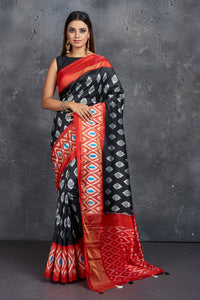 Shop stunning black ikkat silk sari online in USA with red ikkat border. Keep your ethnic wardrobe up to date with latest designer sarees, pure silk sarees, Kanchipuram silk sarees, handwoven sarees, tussar silk sarees, embroidered sarees from Pure Elegance Indian saree store in USA.-full view