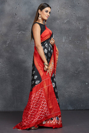 Shop stunning black ikkat silk sari online in USA with red ikkat border. Keep your ethnic wardrobe up to date with latest designer sarees, pure silk sarees, Kanchipuram silk sarees, handwoven sarees, tussar silk sarees, embroidered sarees from Pure Elegance Indian saree store in USA.-side